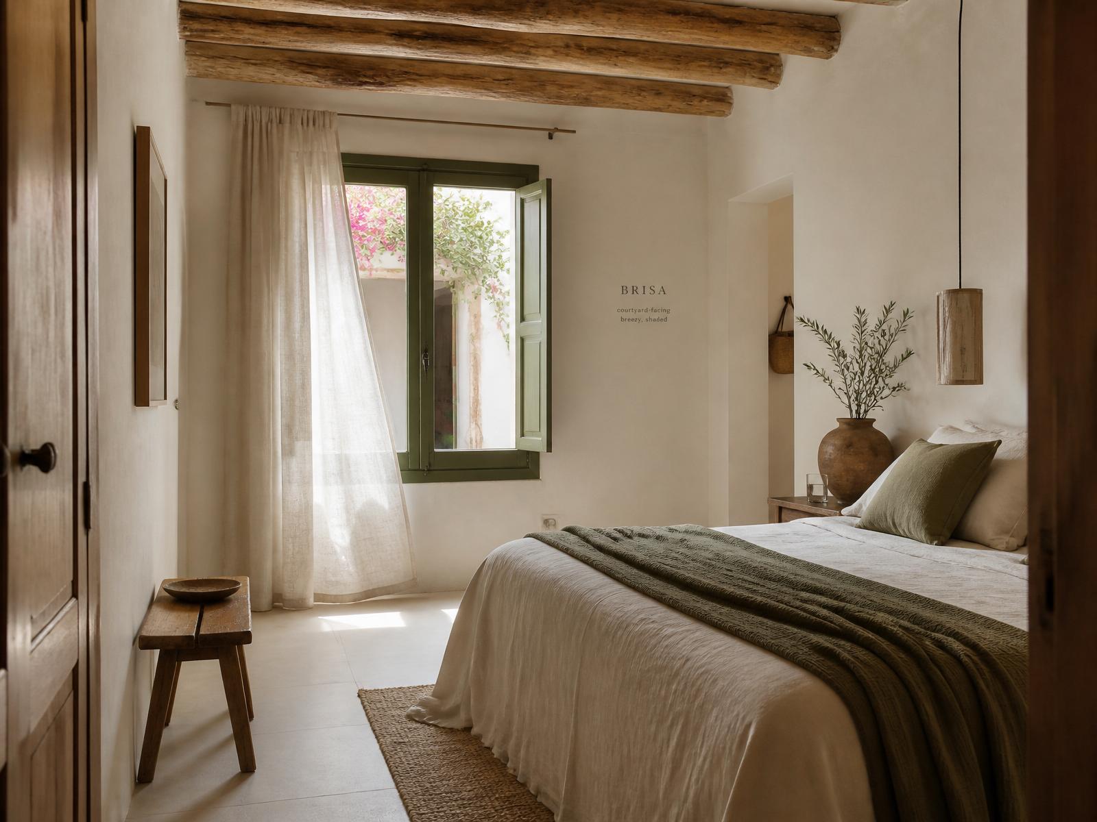 Habitación Brisa — Purissima House, Benissa Habitación Brisa en Purissima House: cortina de lino ondulando frente a ventana de marco verde oliva abierta al patio con buganvilla